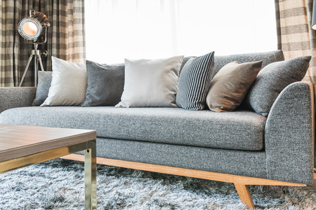 row of pillows on grey sofa with black lamp in living room designの写真素材