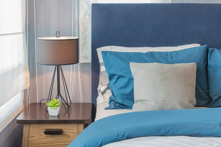 modern blue color tone bedroom with lamp and vase of plant on wooden table sideの写真素材