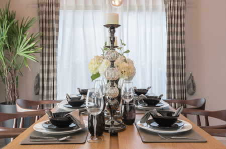 table set on wooden dinning table with vase of plantの写真素材