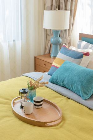 colorful pillows on wooden bed in modern bedroom design with wooden tray of tea setの写真素材
