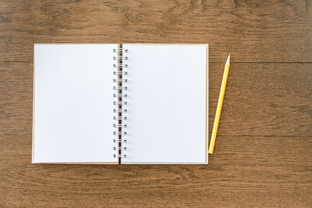blank white notebook on wooden texture background with yellow pencilの写真素材