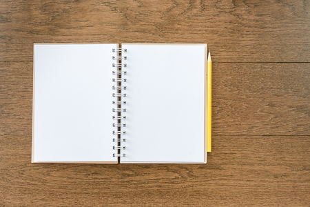 blank white notebook on wooden texture background with yellow pencilの写真素材
