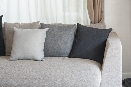 set of pillows on modern sofa with white curtain as backgroundの写真素材