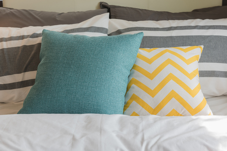 colorful pillows set on bed in modern bedroom style interior design conceptの写真素材