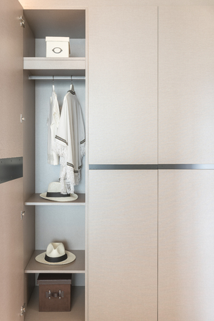white shirts hanging on rail in wooden wardrobe, clothes hanging in closetの写真素材