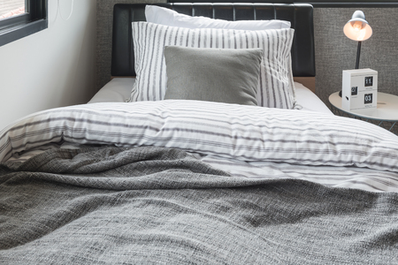 set of pillows with blanket on modern wooden bed in modern bedroom interior design