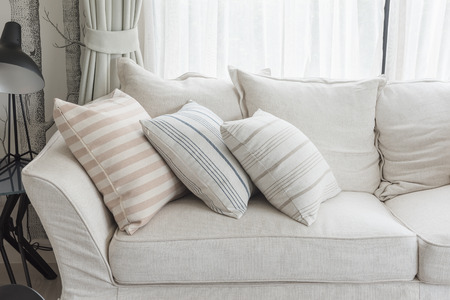 set of pillows on white classic sofa in living room, interior design concept