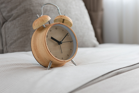 wooden modern alarm clock on bed in modern bedroom designの写真素材