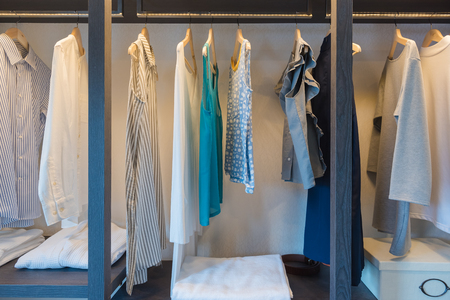 wooden wardrobe in walk in closet with clothes hanging on rail, interior design conceptの写真素材