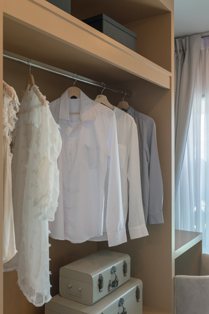 modern closet with clothes hanging on rail, white wooden wardrobe, interior design conceptの写真素材