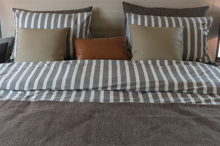 modern bedroom with set of pillows and stripe pattern blanket on bed, interior design decoration conceptの写真素材