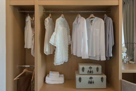 modern closet with clothes hanging on rail, white wooden wardrobe, interior design conceptの写真素材