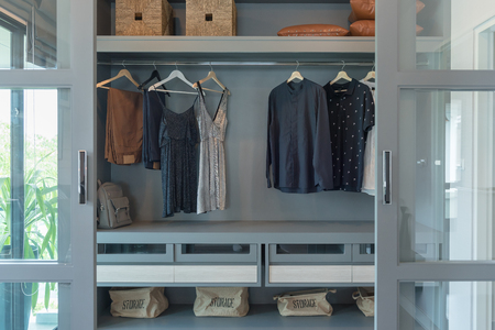 modern closet with clothes hanging on rail, white wooden wardrobe, interior design conceptの写真素材