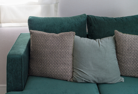 modern cozy sofa in green color tone with set of pillows, interior design concept decoration
