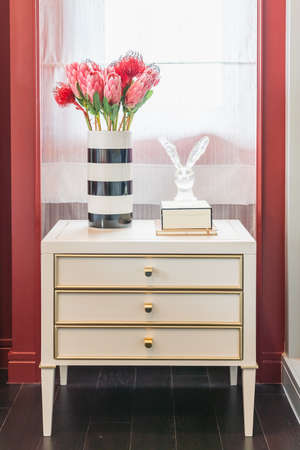 wooden side table in bedroom with vase of flower, classic style furniture, interior decoration...