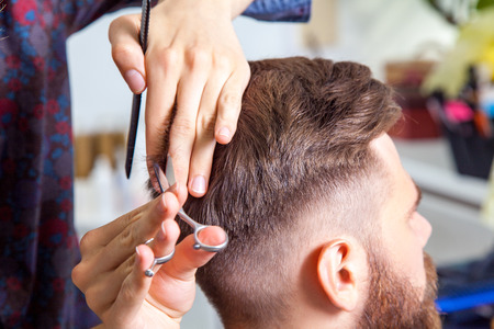 Professional barber styling hair of his clientの写真素材