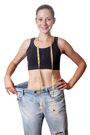 Close-up of slim waist of young woman in big jeans showing successful weight loss, isolated on white background, diet concept.の写真素材
