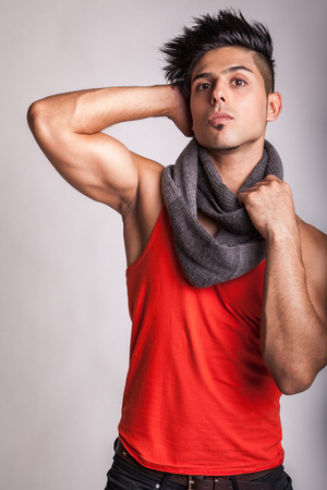 Fashion middle eastern model with scarf posing with his muscular body in studio on gray background.の写真素材