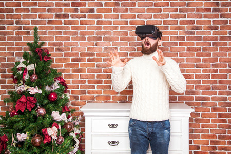 loneliness and illusion of new year. the portrait of bearded man with virtual reality glasses near new year's tree.の写真素材