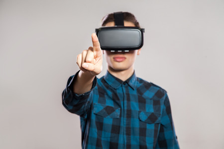 Emotional funny man wearing virtual reality goggles. Studio portrait of video game designer wearing VR headset. studio shot isolated on gray background.の写真素材