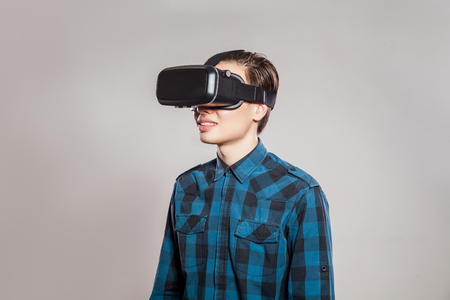Emotional funny man wearing virtual reality goggles. Studio portrait of video game designer wearing VR headset. studio shot isolated on gray background.の写真素材