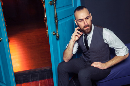 Stylish young fashion model in a suit near door with red light. Business style. Fashionable image. Evening dress. Sexy man standing and looking at the camera. Fashion look.の写真素材