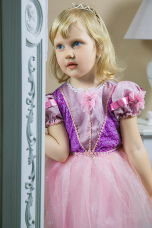 Little happy princess girl in pink dress and crown in her royal room posing and smiling.の写真素材