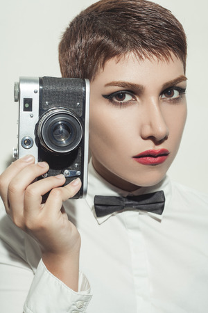 young beautiful woman photographer with camera and  short hair style and classic wear with bow tie.の写真素材