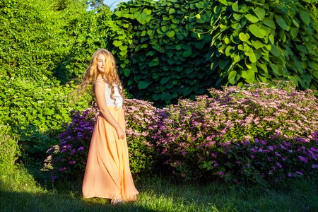 Happy beautiful girl with long light brown hair is posing in the park.の写真素材