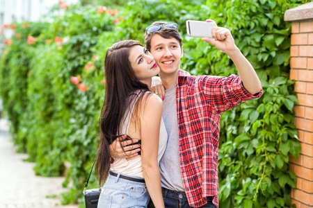 Happy beautiful couple taking a selfie on a mobile phone. huging and have a fun together.の写真素材
