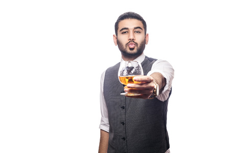 Handsome bearded businessman holding a glass of whiskey. share drink and send kiss. studio shot, isolated on white background.の写真素材