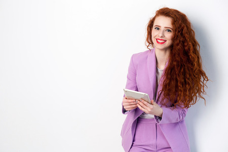 Portrait of successful happy beautiful business woman with red - brown hair and makeup in pink suit...