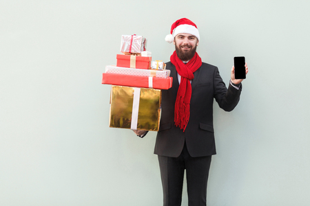 No way! New year sale! Online shopping. Businessman holding hands phone  and looking at camera with smiley face. Indoor, studio shot. Isolated on gray backgroundの写真素材