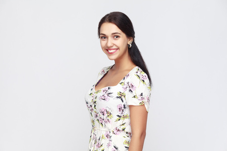 Portrait of happiness woman in flowers dress, looking at camera and toothy smile. Studio shot, isolated on gray backgroundの写真素材