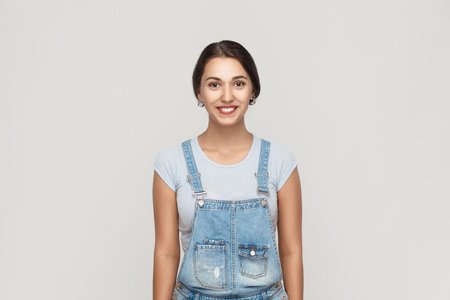 Beauty concept. The attractive brown haired young adult latin woman with perfect clean skin looking and smiling at camera. Isolated studio shot on gray backgroundの写真素材