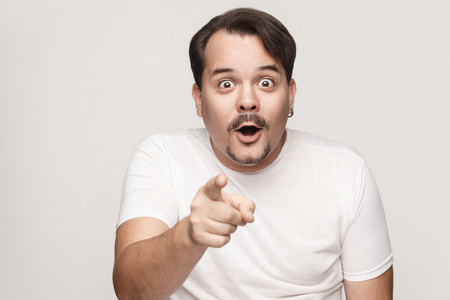 The adult man, opening mouths widely, having surprised shocked looks, pointing finger at camera....