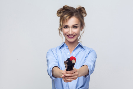 Focus on brush. Happiness  young adult girl showing brush at camera and smiling. Studio shotの写真素材