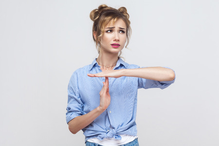 Please break! Time out, stop sign. Young adult blonde girl showing warning sign. Studio shot on gray...