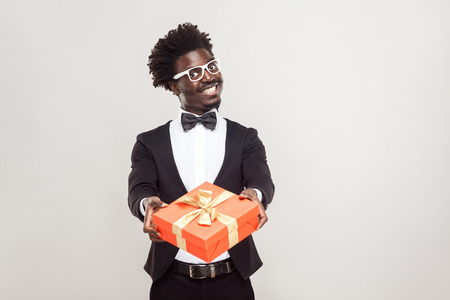 Romantic african businessman showing gift box for valentines day. Studio shot.の写真素材