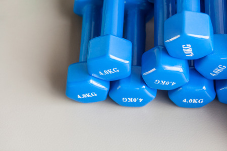 Athletic blue dumbbells folded on the gray floor. Studio shot