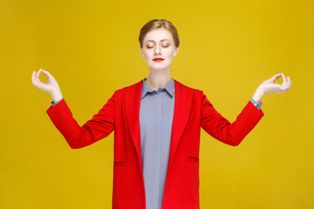 Yoga concept. Red head well dressed woman doing asana. Studio shot, isolated on yellow backgroundの写真素材