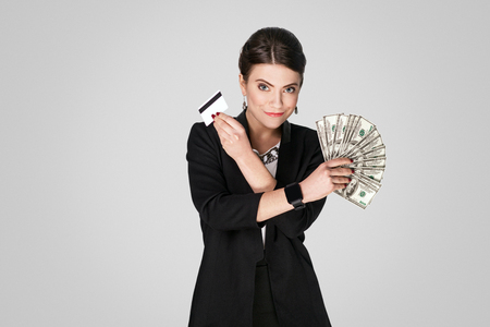 Boss showing at cash, dollar and credit card. Studio shot, indoor. Isolated on grey backgroundの写真素材