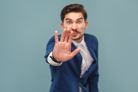Stop. Businessman showing hand ban at camera. Business people concept, richly and success. Indoor, studio shot on light blue backgroundの写真素材