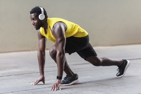 Profile view. African athlete man in running start pose. Outdoor shot, morning. Spring or summerの写真素材
