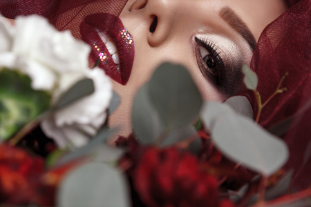 Portrait of young woman with fashionable makeup and eucalyptus bouquet, studio indoor shot. looking at camera.の写真素材