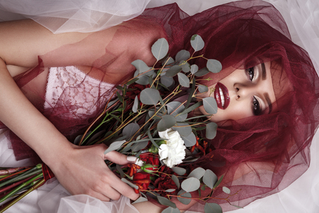 Portrait of young woman with fashionable makeup and eucalyptus bouquet, top view , studio indoor shot. looking at camera.の写真素材