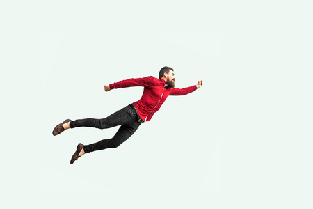 Superman style. Enthusiasm concept. strong bearded businessman felt himself a superhero and flying up. indoor studio shot isolated on gray background.の写真素材