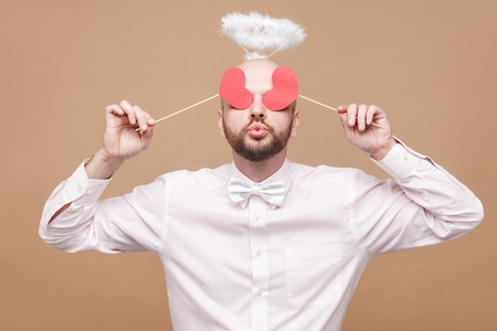 Happy handsome middle aged bald bearded angel in shirt and white halo on head standing and closing...