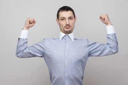I am strong. Portrait of serious proud handsome bristle businessman in classic blue shirt standing...