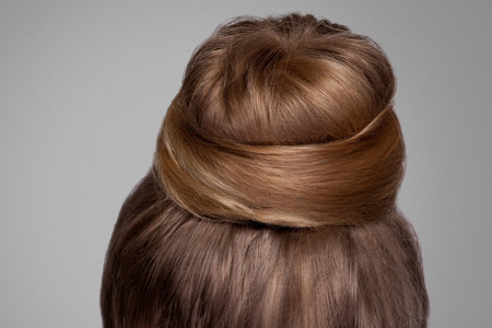Back side view closeup portrait with creative elegant brown collected hairstyle, bun hair. indoor studio shot, isolated on grey background.の写真素材